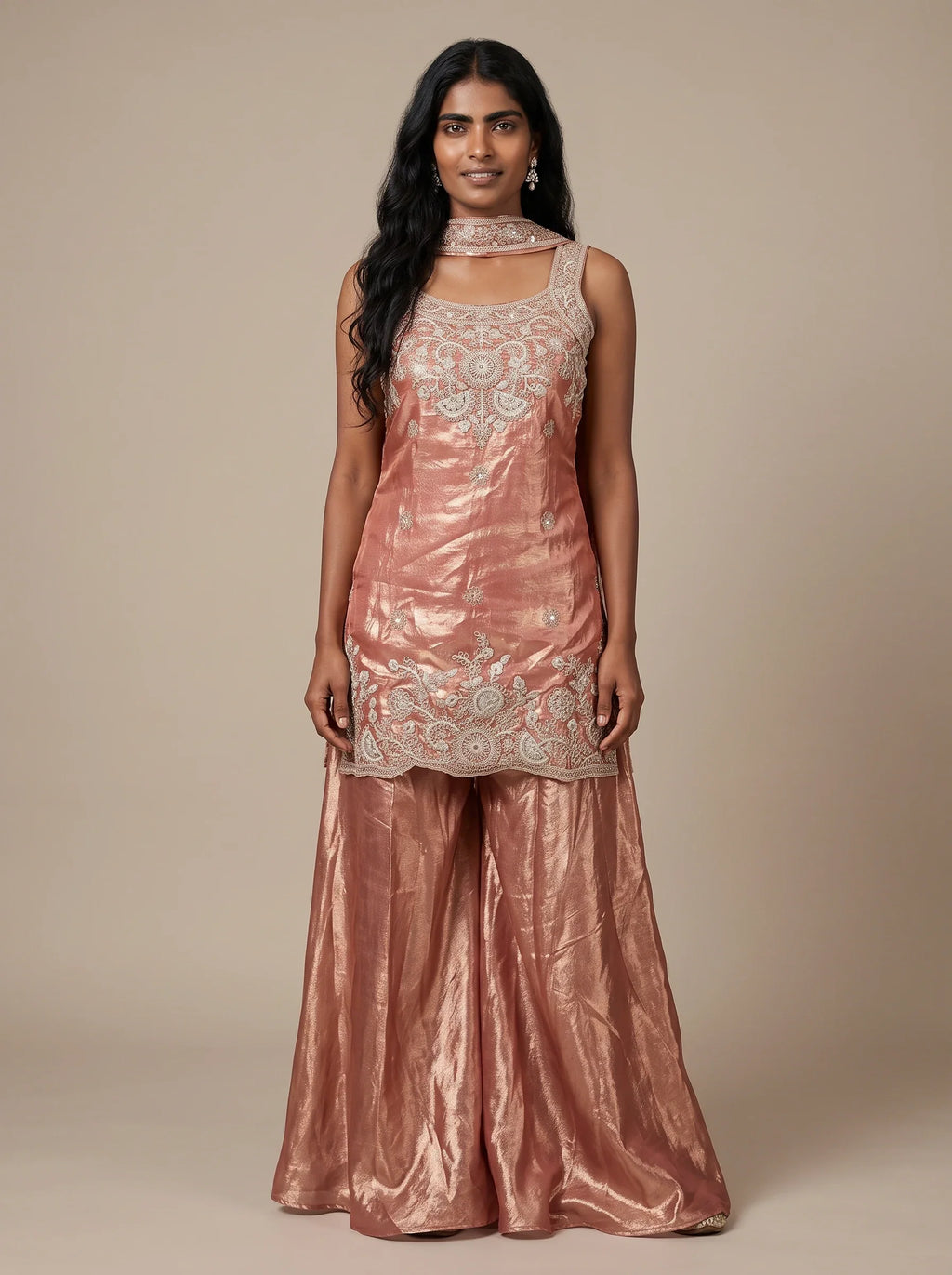Model wearing a peach tissue silk embroidered sharara set with flared bottoms and matching dupatta.