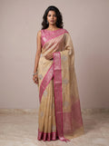 Model wearing a light gold kota tissue saree with pink zari border and embroidered leaf motifs