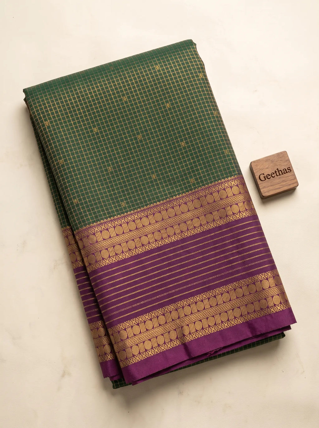 Folded deep green soft silk saree with a purple and gold-toned woven border