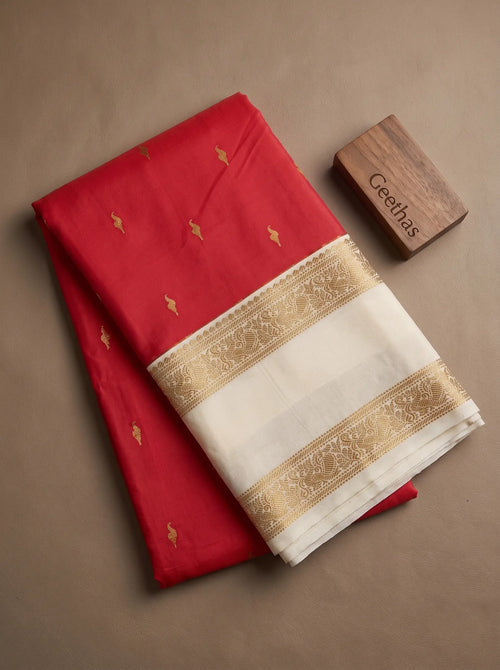 Folded bright pink soft silk saree with gold-toned motifs and ivory decorative border