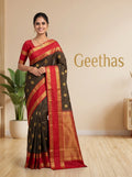 Model wearing a brown soft silk saree with gold-toned woven motifs and a deep red border
