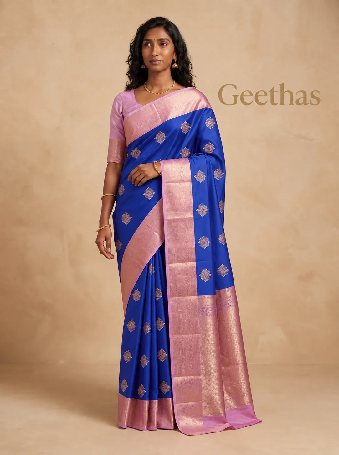 Model wearing royal blue soft silk saree with gold-toned woven motifs and pink border