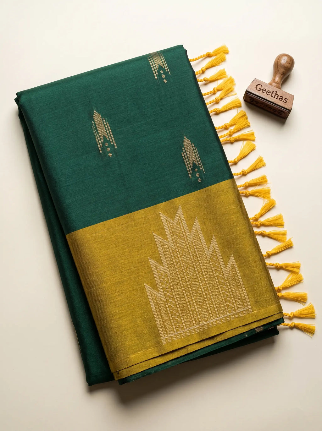 Folded emerald green soft silk saree with gold-toned woven motifs, mustard-gold geometric pallu and tassel finish