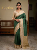 Model wearing a deep green soft silk saree with gold-toned grid motifs and an ivory-beige woven border