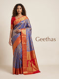 Model wearing a royal blue soft silk saree with floral woven motifs and a contrasting red-orange gold-toned border